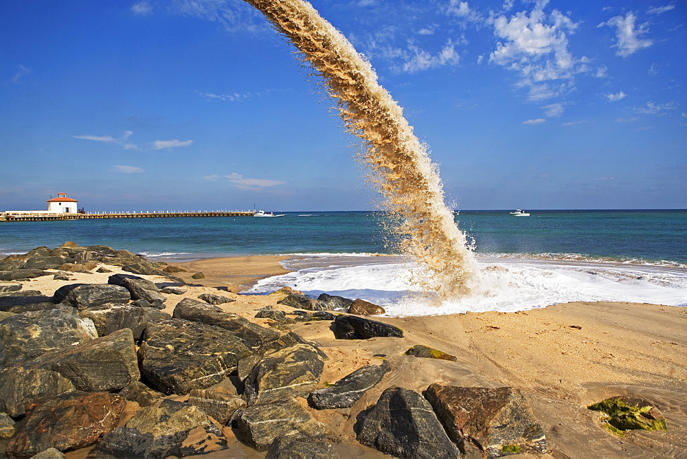 Pipe spraying sand on beach