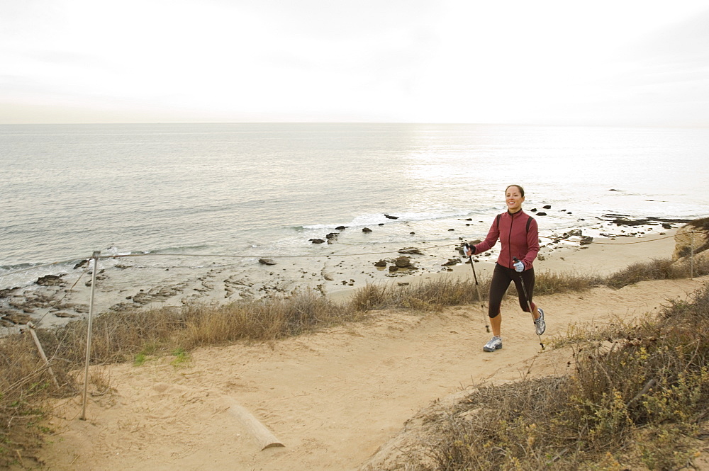 Hispanic woman pole walking along coast in California, United States