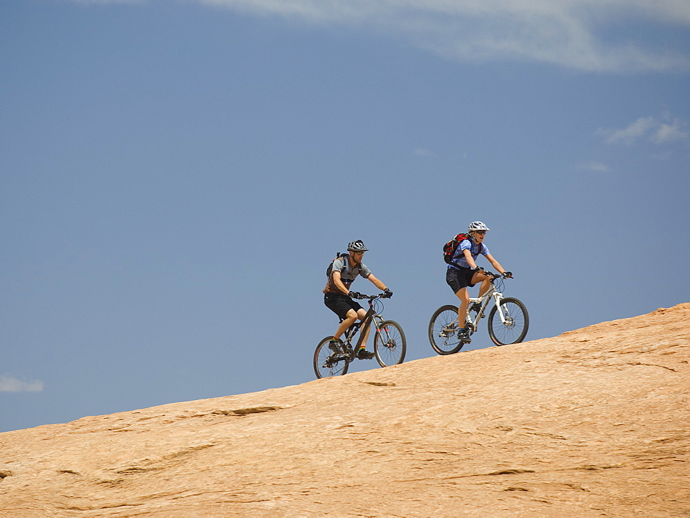 Couple riding mountain bikes in desert