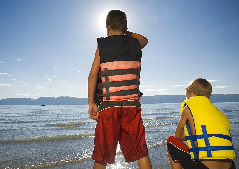 Boys in life jackets looking out over lake, Utah, United States