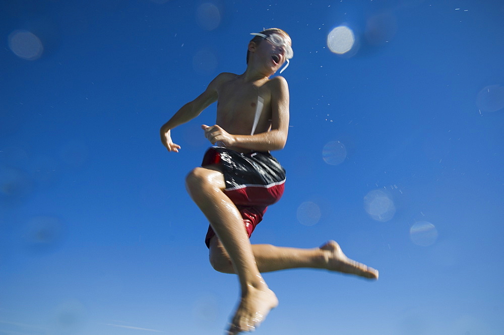 Boy in bathing suit jumping in air, Utah, United States