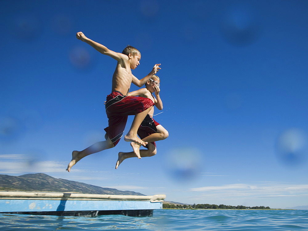 Brothers jumping off dock into lake, Utah, United States