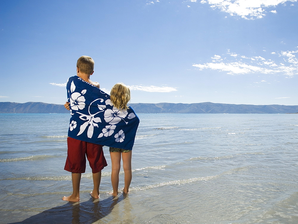 Brother and sister wrapped in beach towel, Utah, United States