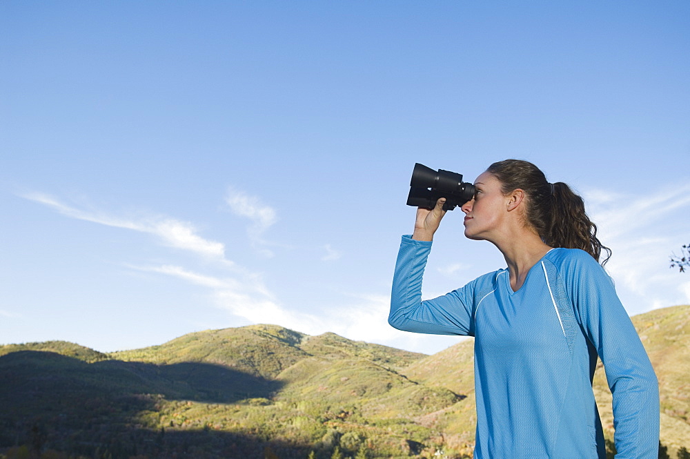 Woman looking through binoculars, Utah, United States