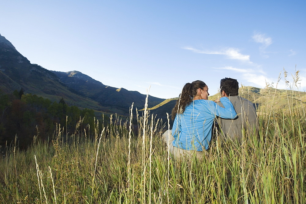 Couple sitting on hillside, Utah, United States