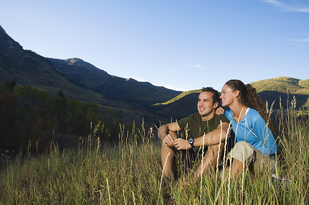 Couple sitting on hillside, Utah, United States