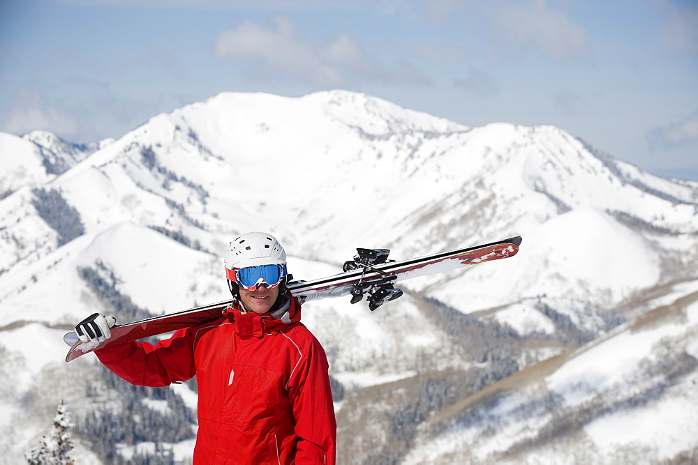 Man holding skis on shoulder