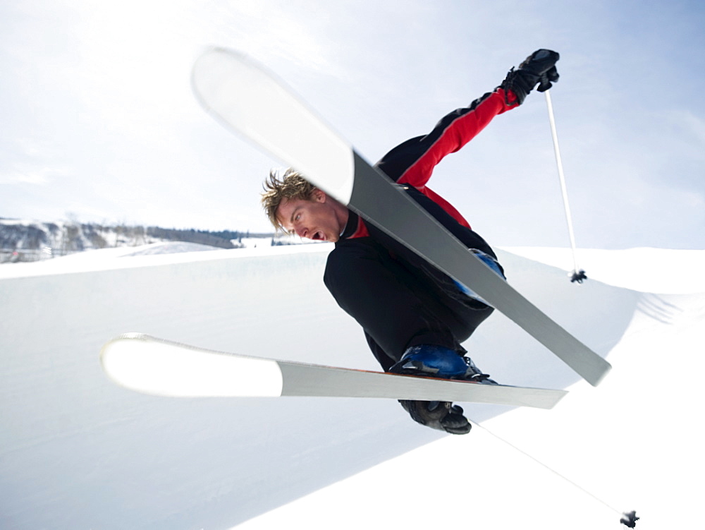 Skier jumping off lip of half-pipe