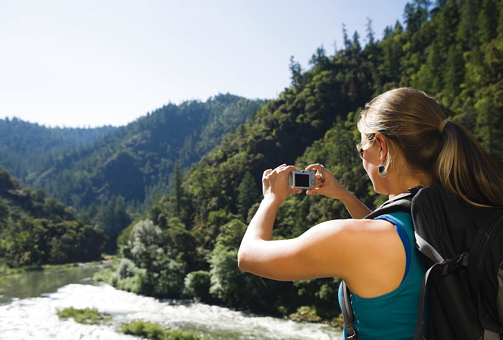 Hiker photographing river scene