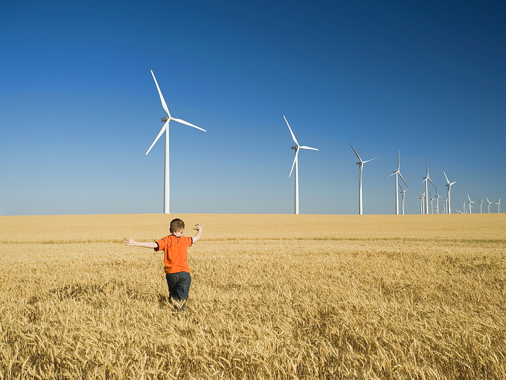 Boy running through field on wind farm