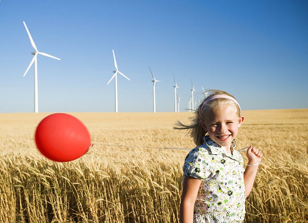 Girl holding balloon on wind farm