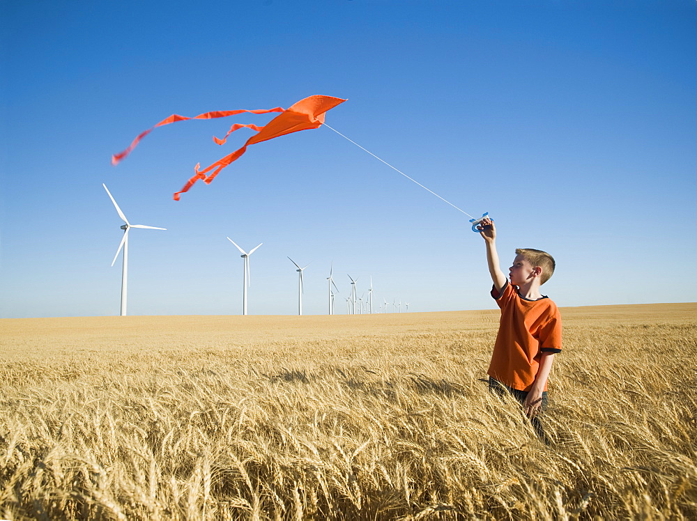 Boy running with kite on wind farm