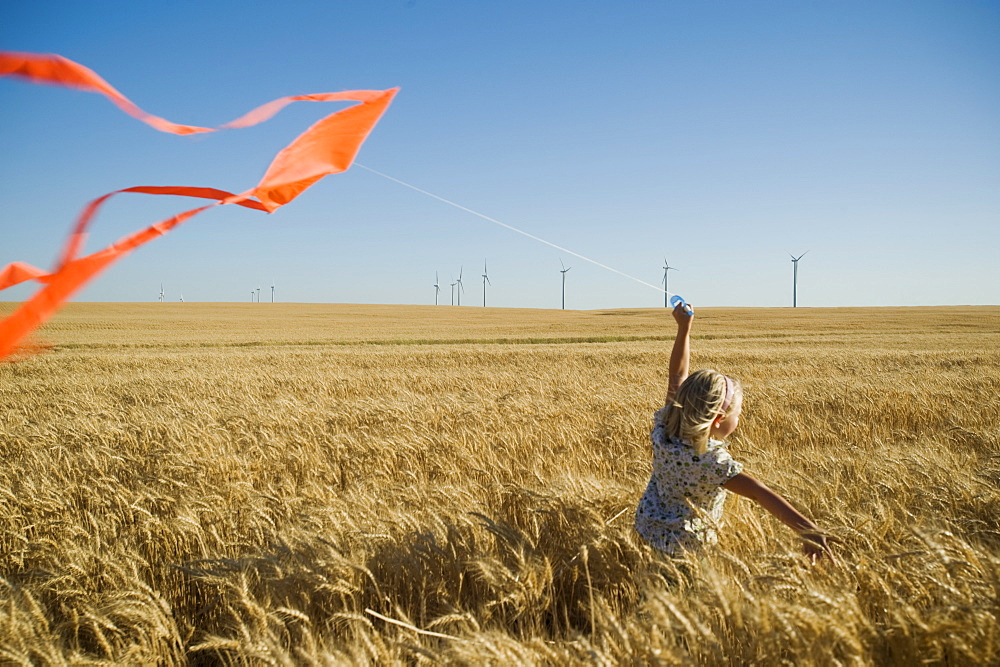 Girl running with kite on wind farm