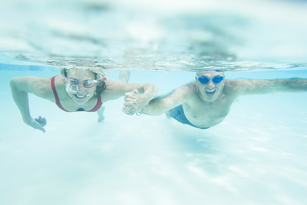 Couple swimming underwater and holding hands