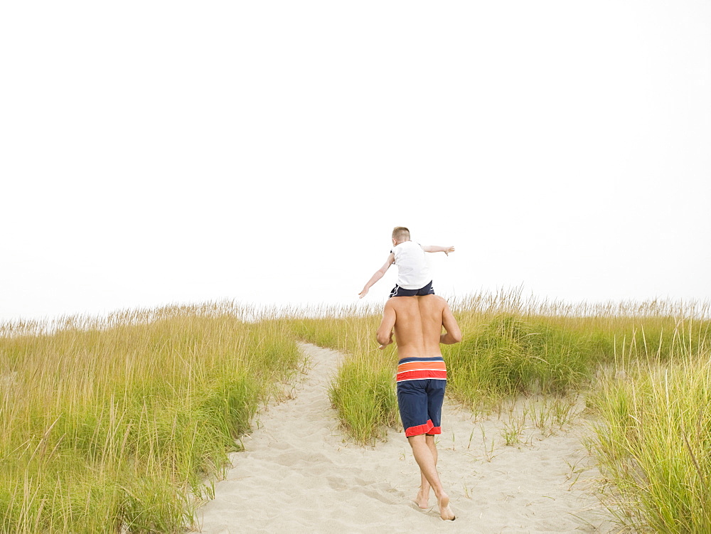 Father carrying son on shoulders at beach