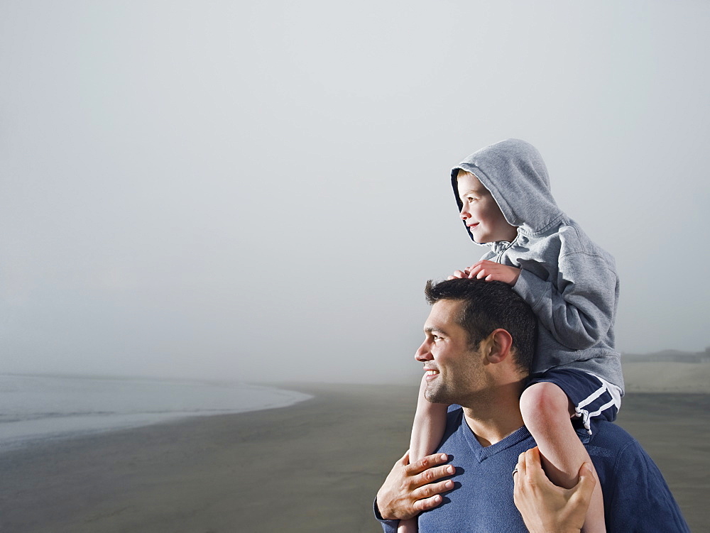 Father carrying son on shoulders on beach