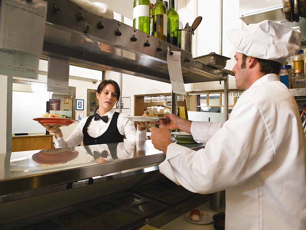 Chef giving waitress plates of food