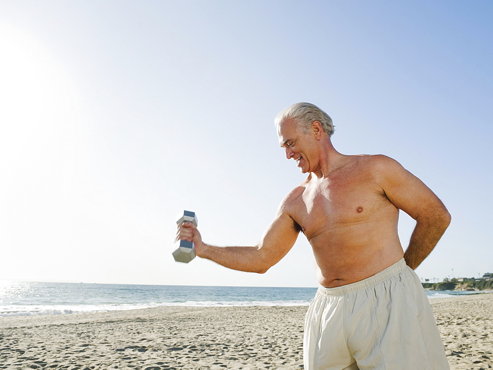 Man exercising with dumbbell on beach