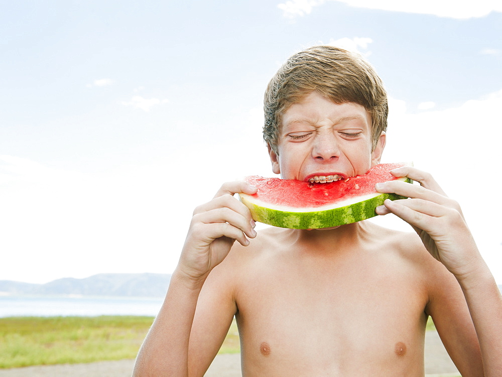 Boy (12-13) eating watermelon