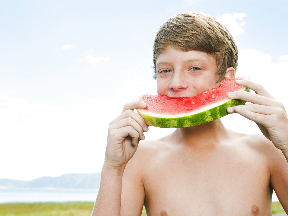 Boy (12-13) eating watermelon