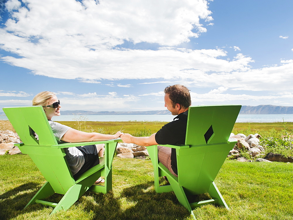 Young couple sitting on meadow holding hands