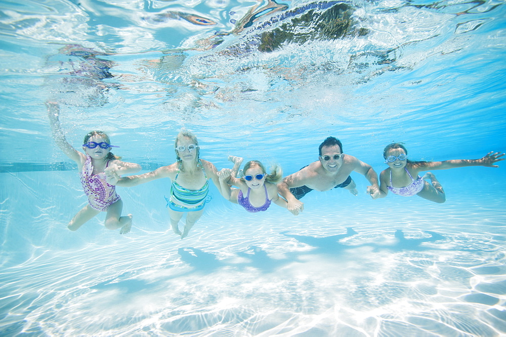 Family with three daughters (4-5,6-7,8-9) swimming underwater