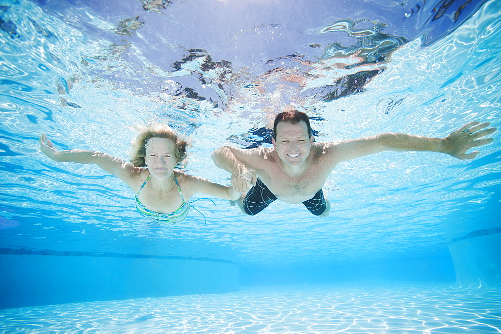 Mid adult couple swimming underwater