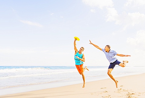 Young men playing plastic disc on beach, Jupiter, Florida