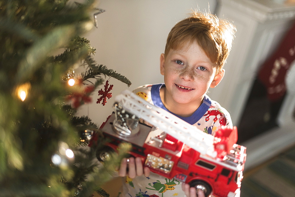 Portrait of boy (6-7) holding toy firetruck