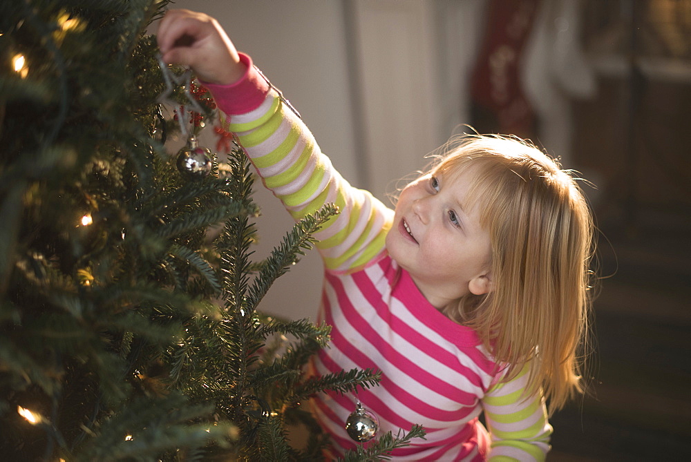 Girl (4-5) decorating christmas tree