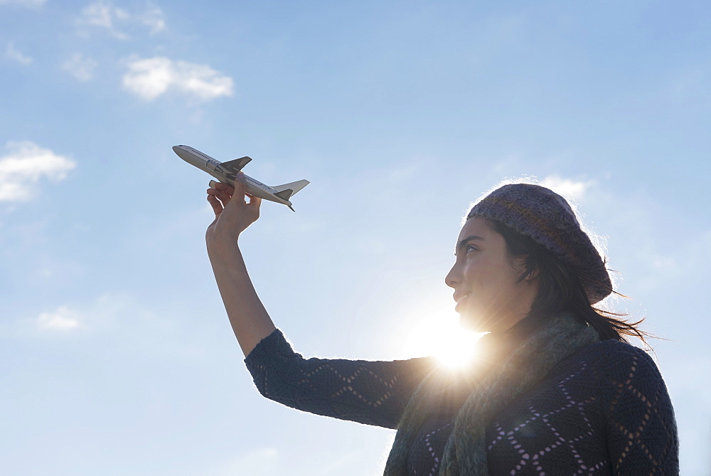 Side view of young woman holding model airplane