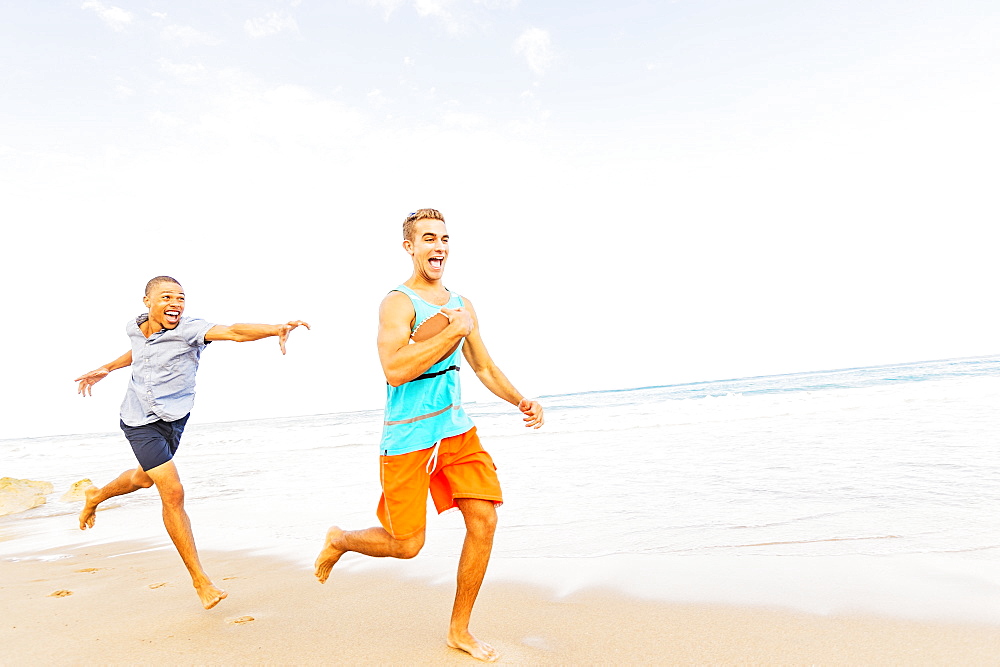 Young men playing with football on beach, Jupiter, Florida