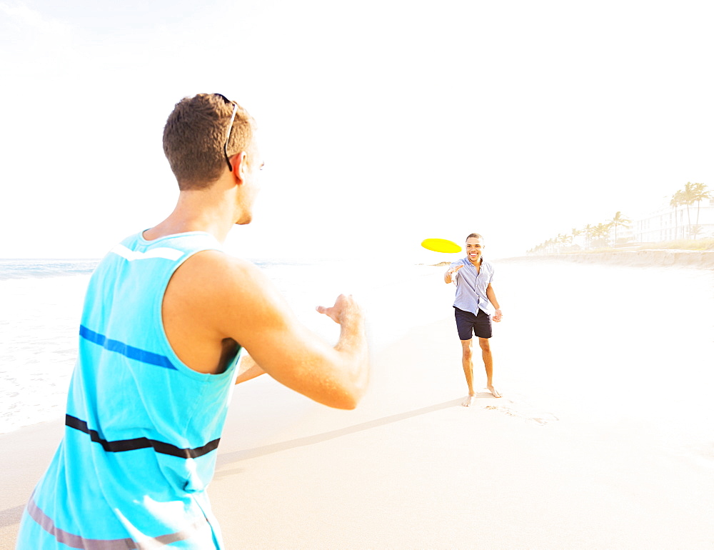 Young men playing plastic disc on beach, Jupiter, Florida