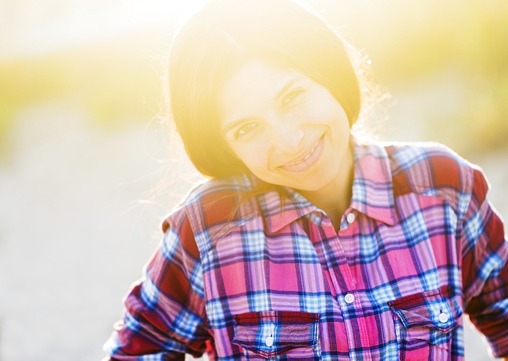 Portrait of young woman in sunlight, smiling 