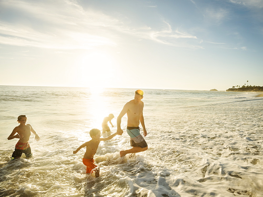 Father on beach with his three sons (6-7, 10-11, 14-15), Laguna Beach, California