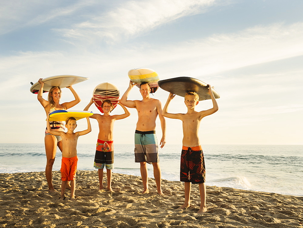 Portrait of family with three children (6-7, 10-11, 14-15) with surfboards on beach, Laguna Beach, California