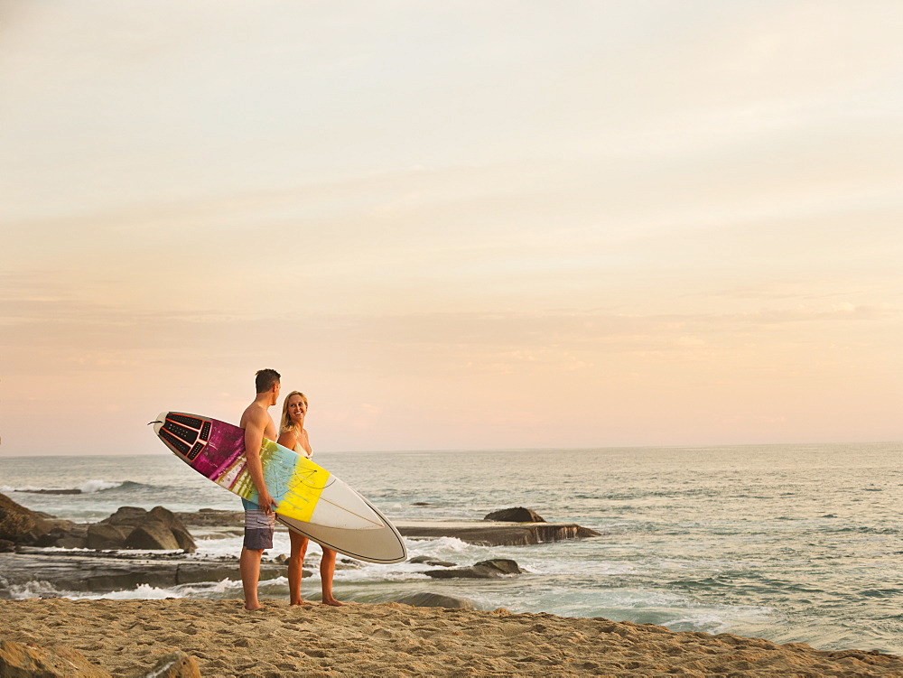 Mid-adult couple talking on beach at sunset, Laguna Beach, California