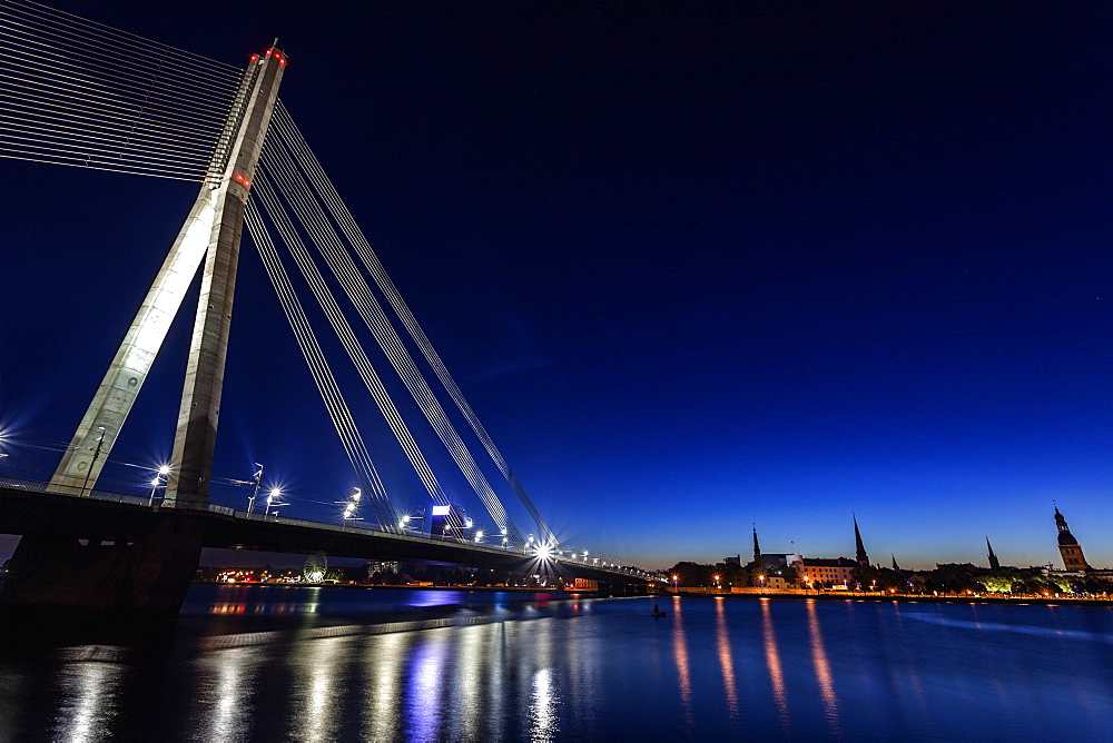 Illuminated Vansu Bridge reflecting in river, Latvia