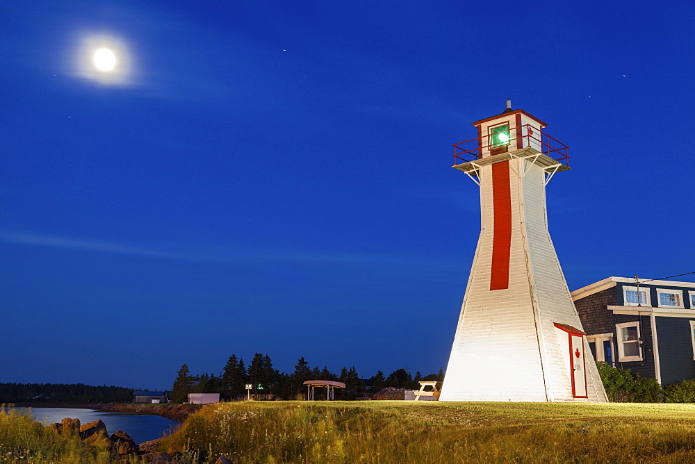 Lighthouse on grassy hill under full moon, Prince Edward Island, New Brunswick, Canada