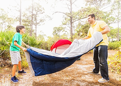 Father and son (12-13) preparing sleeping bag for camping, Jupiter, Florida