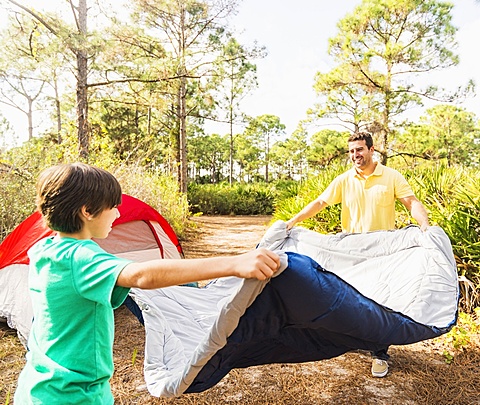 Father and son (12-13) preparing sleeping bag for camping, Jupiter, Florida