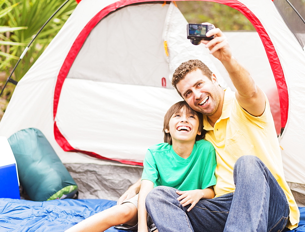 Father and son (12-13) taking selfie in front of tent, Jupiter, Florida