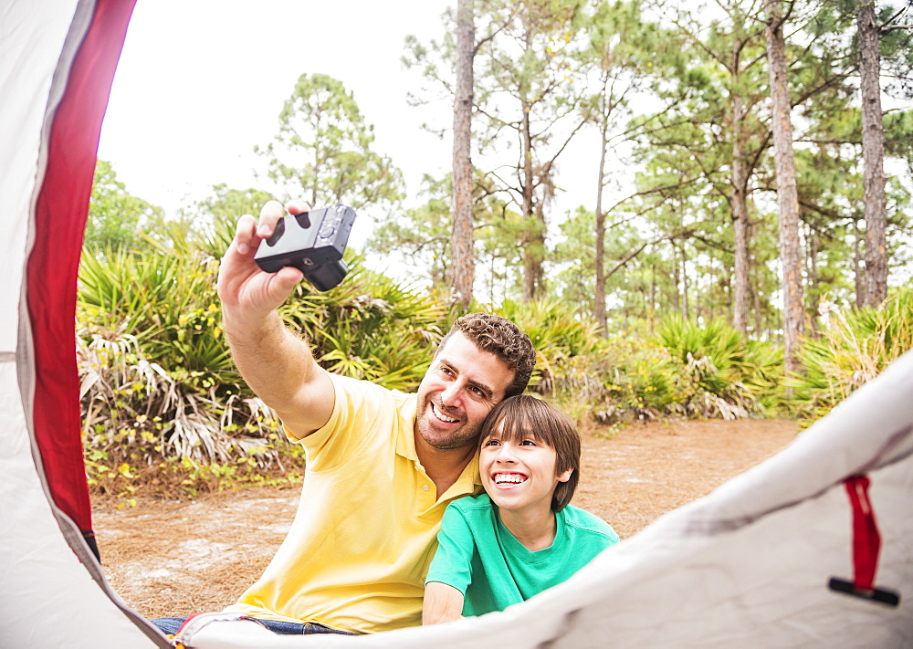 Father and son (12-13) taking selfie in front of tent, Jupiter, Florida