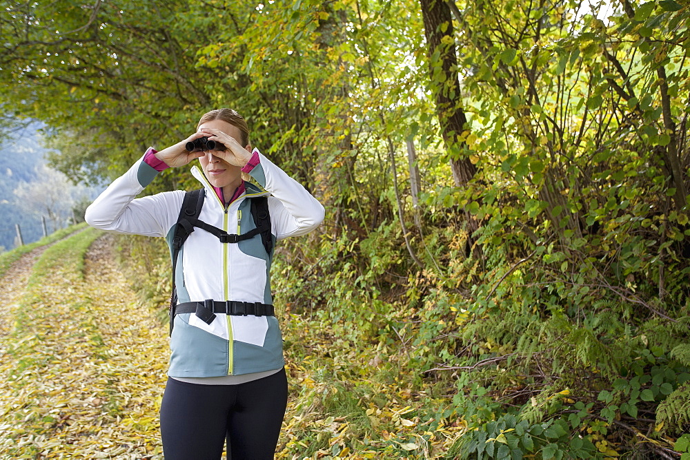 Woman looking through binoculars, Austria, Salzburger Land, Maria Alm