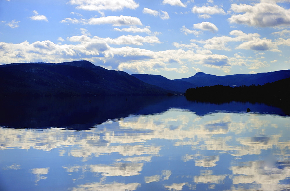 Symmetrical view of blue sky and clouds reflecting in lake, Lake George, New York