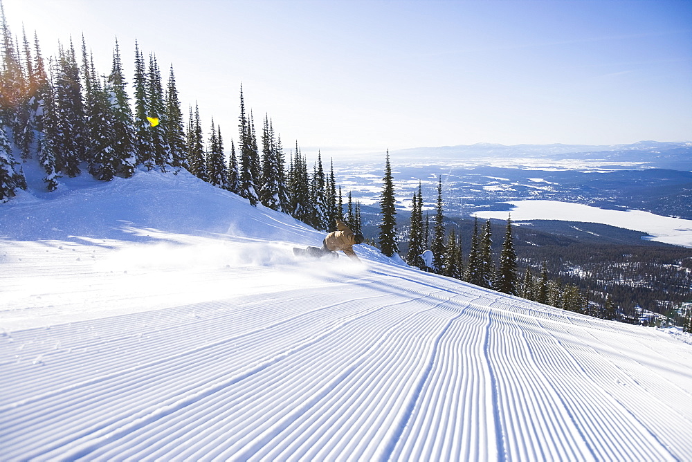 Snowboarder on side of ski slope, Whitefish, Montana, USA