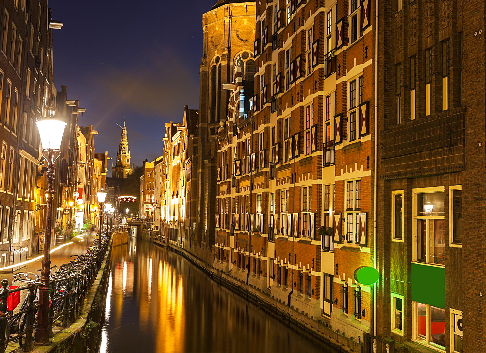 Illuminated buildings by canal at night, Amsterdam, North Holland, Netherlands