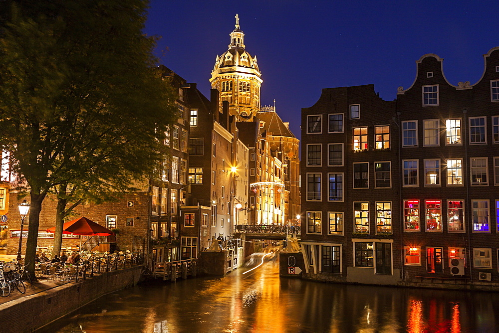Illuminated buildings by canal at night, Amsterdam, North Holland, Netherlands
