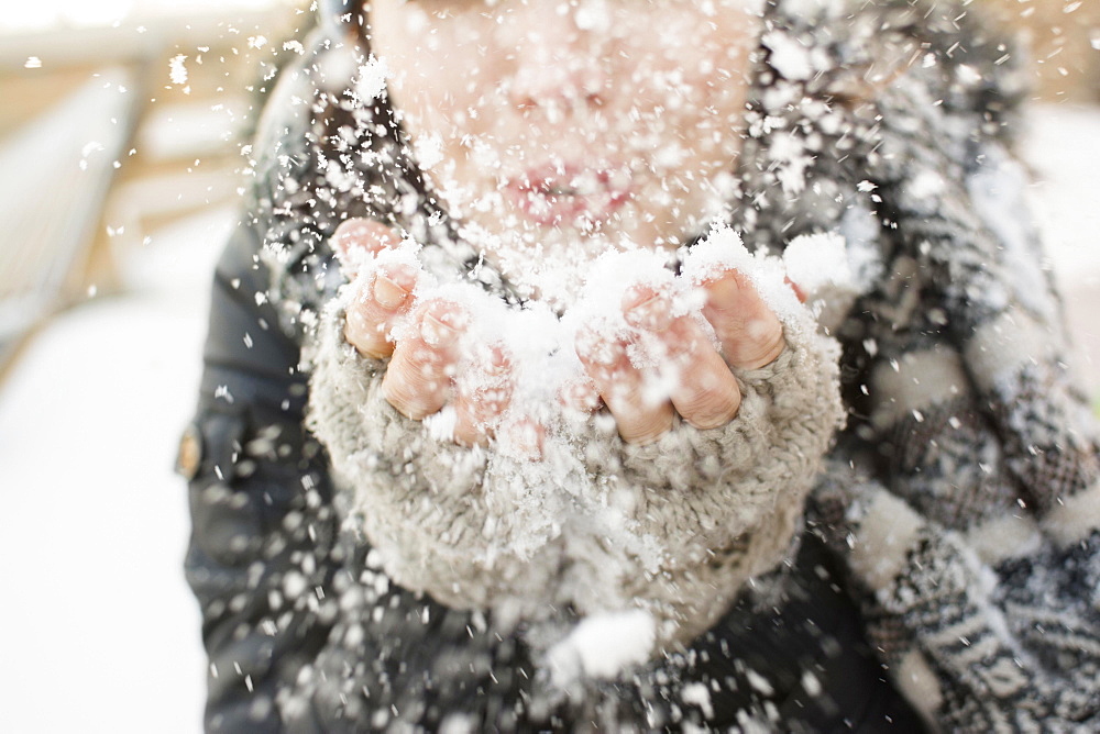 Woman blowing snow towards camera