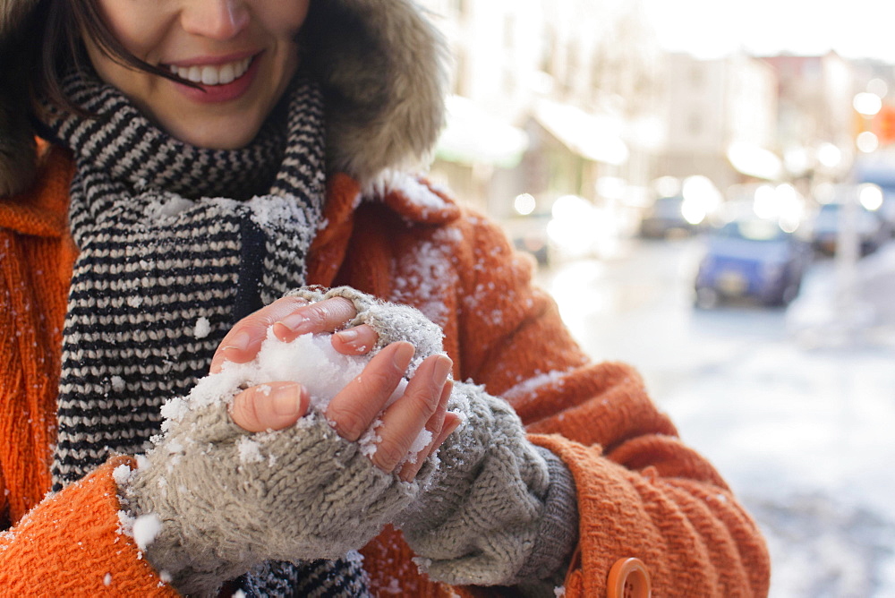 Woman making snowball in street, Brooklyn, New York,USA